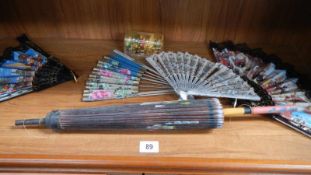 A parasol and quantity of fans.