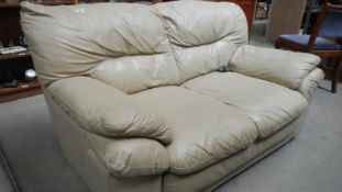A 2 seat cream leather sofa.