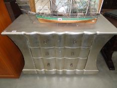 A silver coloured chest of drawers.