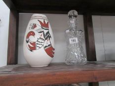 A cut glass decanter and an art pottery vase.