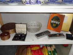 A shelf of miscellaneous including place mats, glass bowl etc.