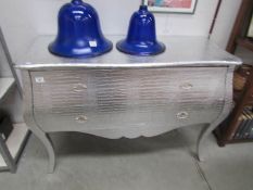 A silver coloured chest of drawers.