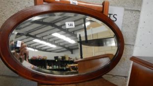 An oval mahogany inlaid bevel edged mirror.