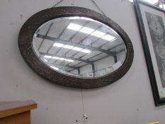 An oval bevel edged mirror in oriental style frame.