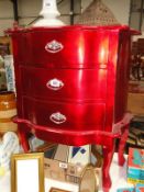A red 3 drawer bedside chest.
