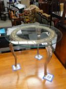 A glass topped table with ornate metal base.