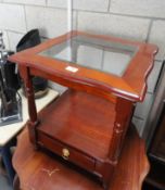 A square table with glass top and base with drawer