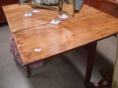 A 19th c drop side faded mahogany table on casters