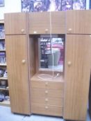 A teak effect double wardrobe with central section of drawers and cupboard