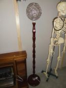 A mahogany standard lamp with silver wire ball shade