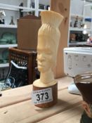 A tribal bone carved head figure on wooden plinth