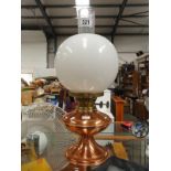 A copper oil lamp with funnel and globe shade