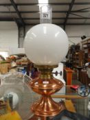 A copper oil lamp with funnel and globe shade
