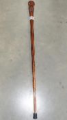 A wooden walking stick with carved kiwi