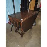 A dark wood stained drop leaf dining table
