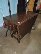 A dark wood stained drop leaf dining table