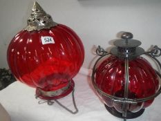 A red glass and metal hanging shade together with a red glass and metal candle lantern,.