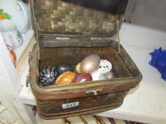 A quantity of decorative eggs and a basketware casket.
