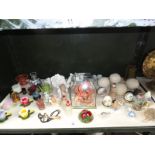 A shelf of assorted items including ceramic flowers, paperweight, scent bottles etc.
