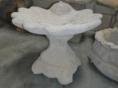 A shell bird bath with decorative base.