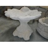 A shell bird bath with decorative base.