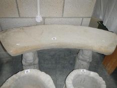 A curved stone seat on squirrel plinths.