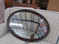 An oval framed bevel edged mirror.