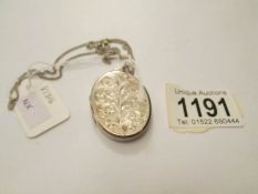 A heavy front opening silver locket with engraving and on silver chain.