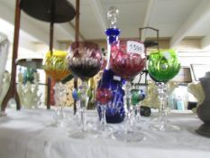 A cut glass coloured decanter and glasses.