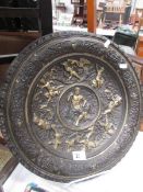 A metal plaque depicting Grecian style figures.