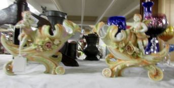 A pair of continental porcelain 'Horn of Plenty' vases surmounted cherubs.