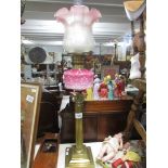 A brass Corinthian column oil lamp with pink glass font.