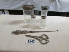 A silver topped salt & pepper, 2 silver topped vanity pots, a button hook and scissors.