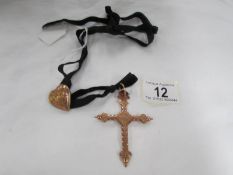 A yellow metal cross pendant and heart shaped ribbon locket on velvet strap.