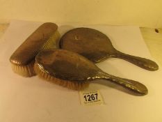 A silver backed hand mirror and 2 silver backed brushes.