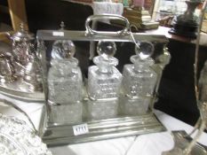 A silver plate 3 bottle tantalus complete with decanters,.