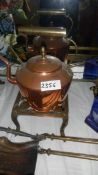 An old copper kettle on a brass trivet.
