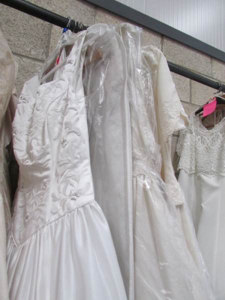 Approximately 10 wedding gowns in various sizes.