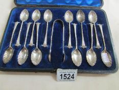 A cased set of 12 Mappin Bros. teaspoons with sugar tongs.