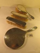 A silver backed hand mirror and 3 silver backed brushes.