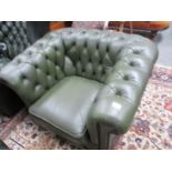 A green leather Chesterfield chair.