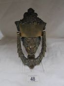 A brass mask door knocker.