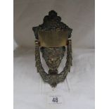 A brass mask door knocker.