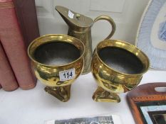 An arts and crafts embossed jug together with a pair of brass planters with dolphin supports.