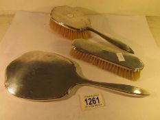 A silver backed hand mirror and 2 silver backed brushes.