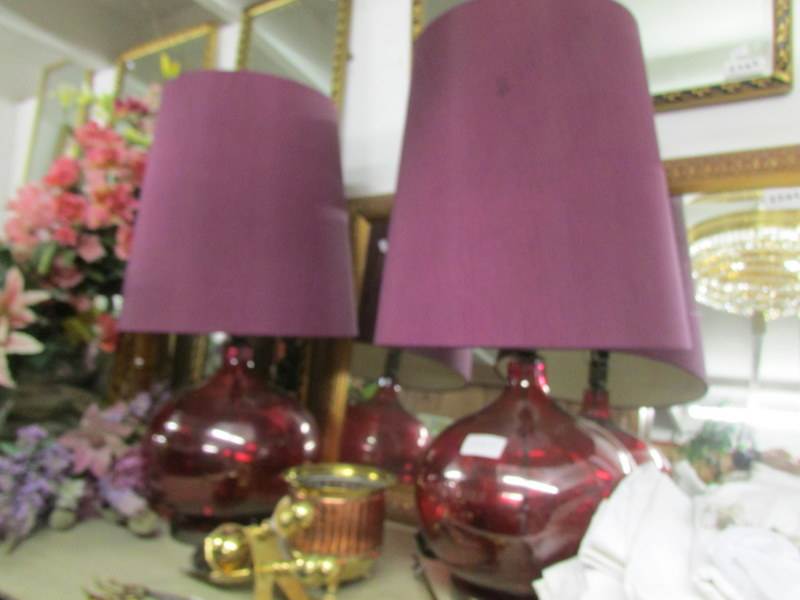 A pair of impressive red glass table lamps with shades.