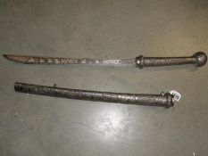 An ornate sword with engraved blade and with possibly silver hilt and scabbard but unmarked.