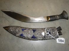 A Kukri with silver overlaid scabbard complete with skinning knives.