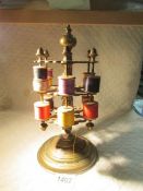 A Victorian brass cotton reel stand with cottons.