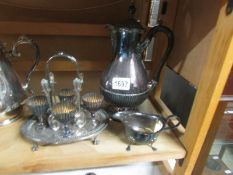 A silver plate water jug, egg cup stand and cream jug.